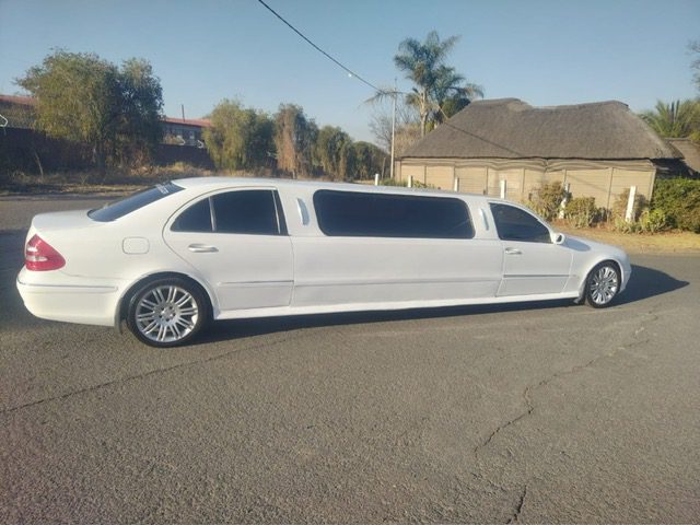 Sleek white 8-seater E-Class limousine parked in front of a stylish venue in Johannesburg, ready for a luxurious night out